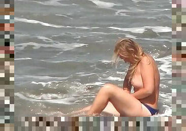 Leggy brunette is getting naked on the beach