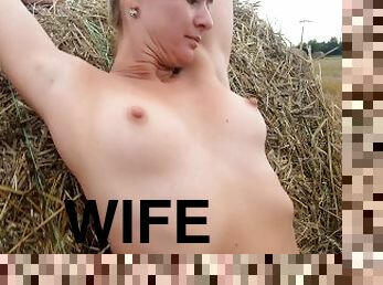 Naked girl playing with a bale of straw