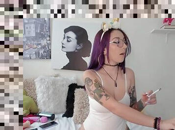 Sexy unicorn girl with an alternative look and glasses lights a cigarette during her webcam show